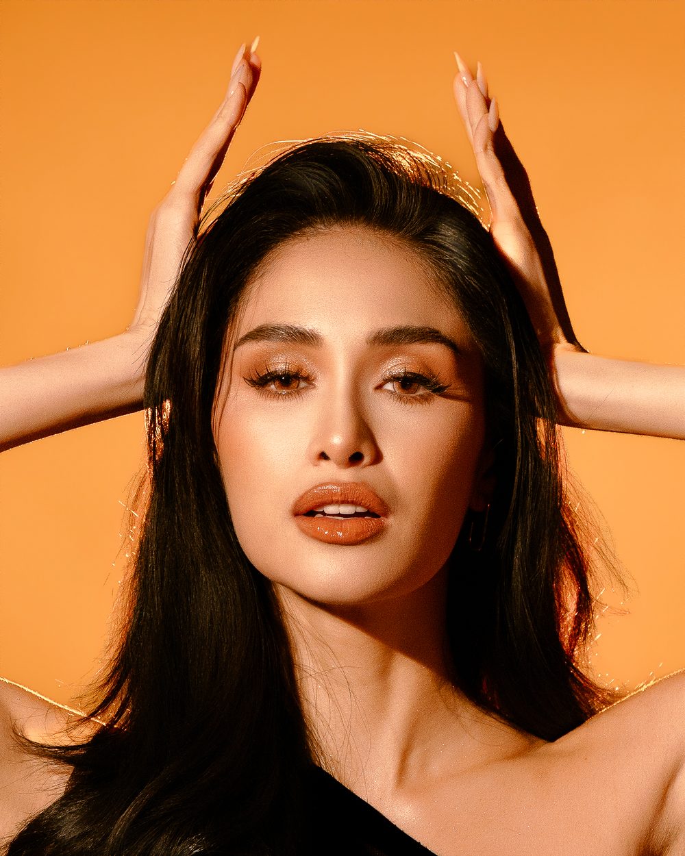 Beauty portrait of Nicole Borromeo against an orange backdrop