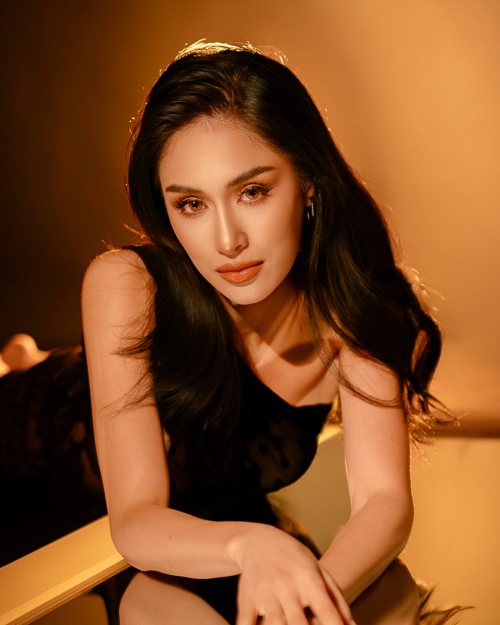 Nicole Borromeo leaning on a mirrored table in warm light